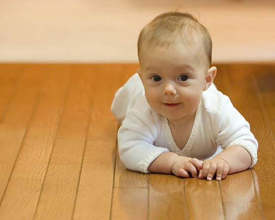 A baby laying on the ground in front of a wall.