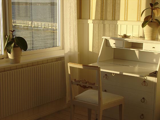A chair and desk in front of a window.